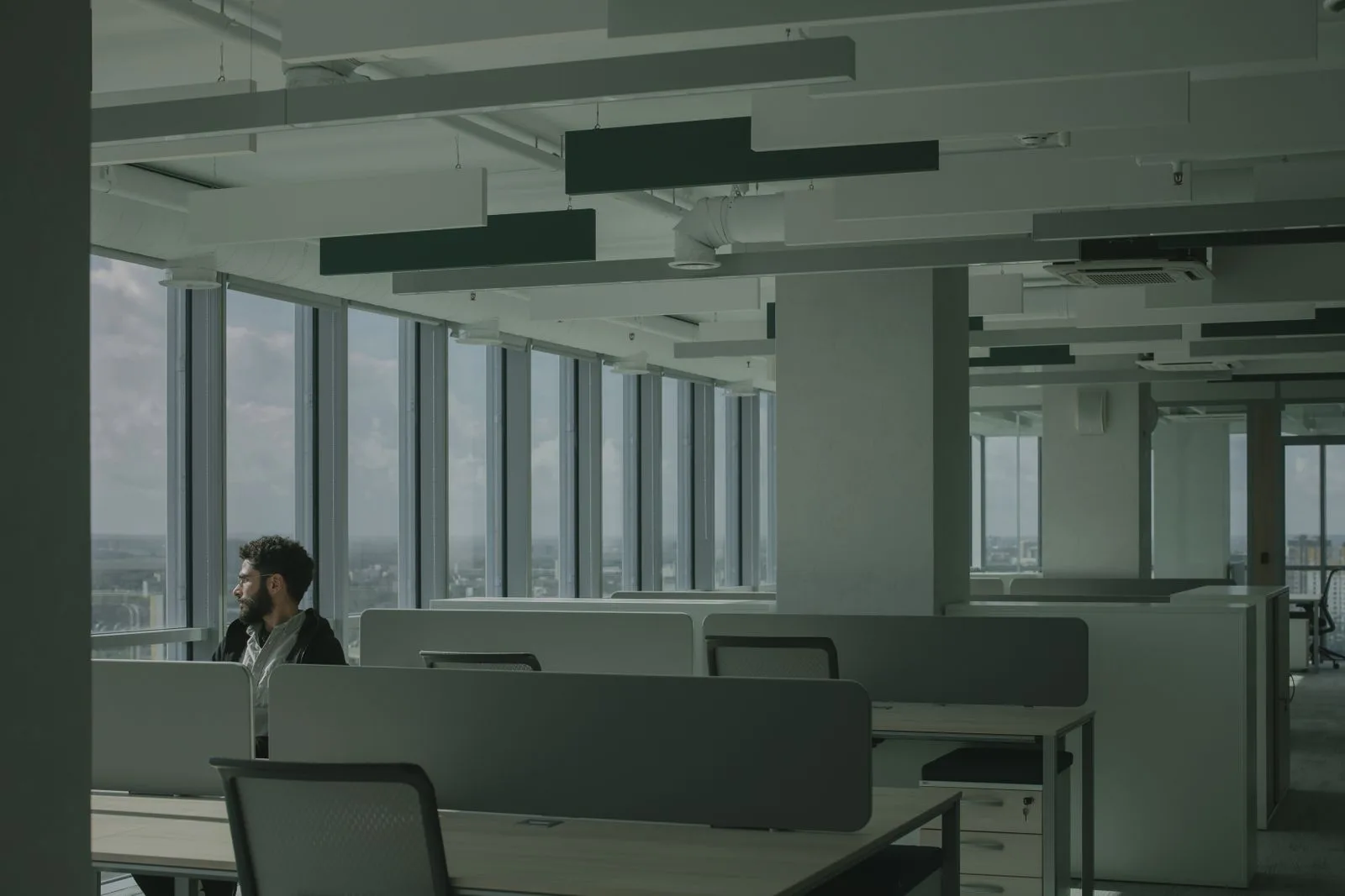 A lone professional sitting in a vast, empty open-plan office — the isolation of building alone