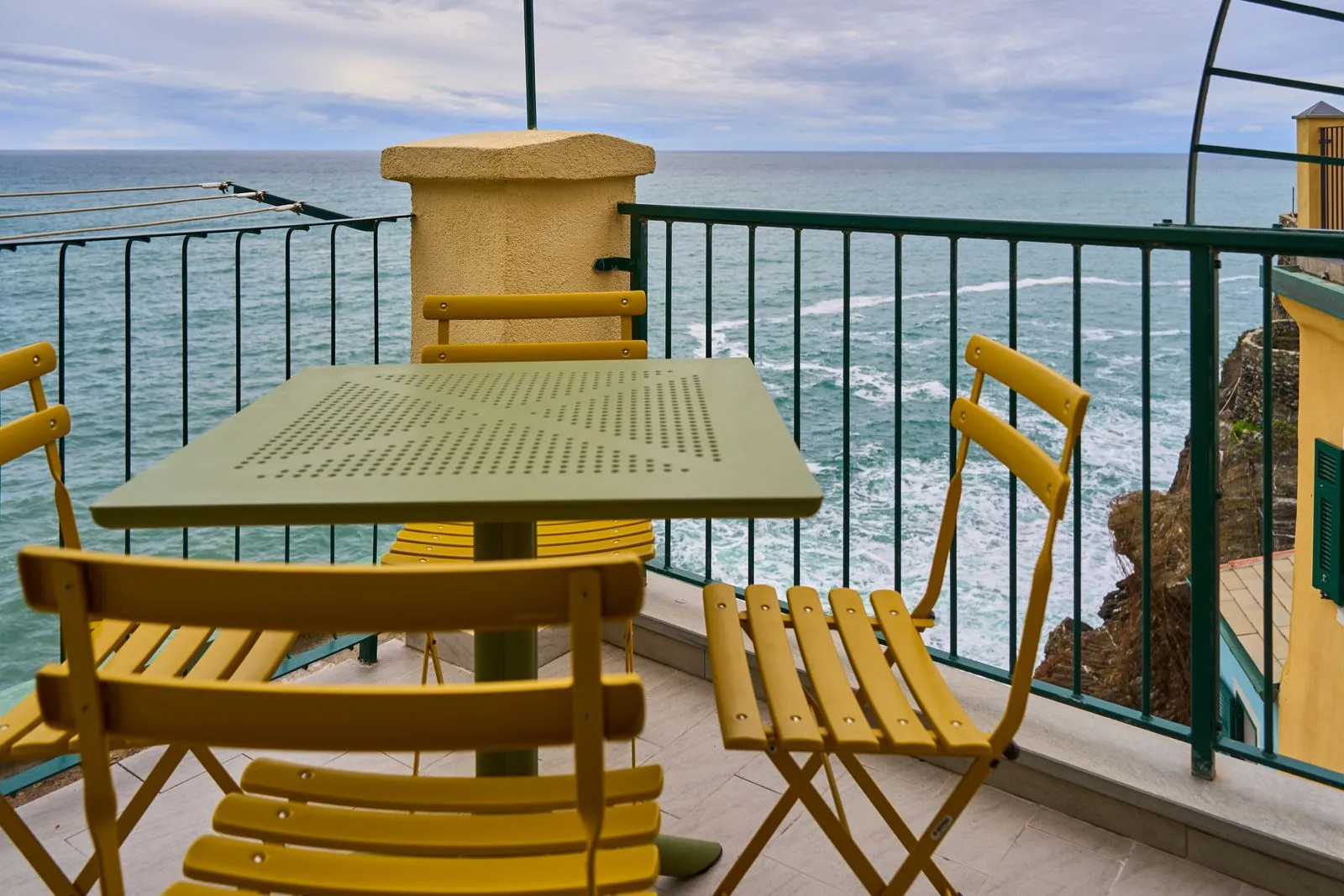 An empty seaside terrace with ochre cafe chairs and a turquoise Mediterranean sea, the quiet setting of a workation between work sessions